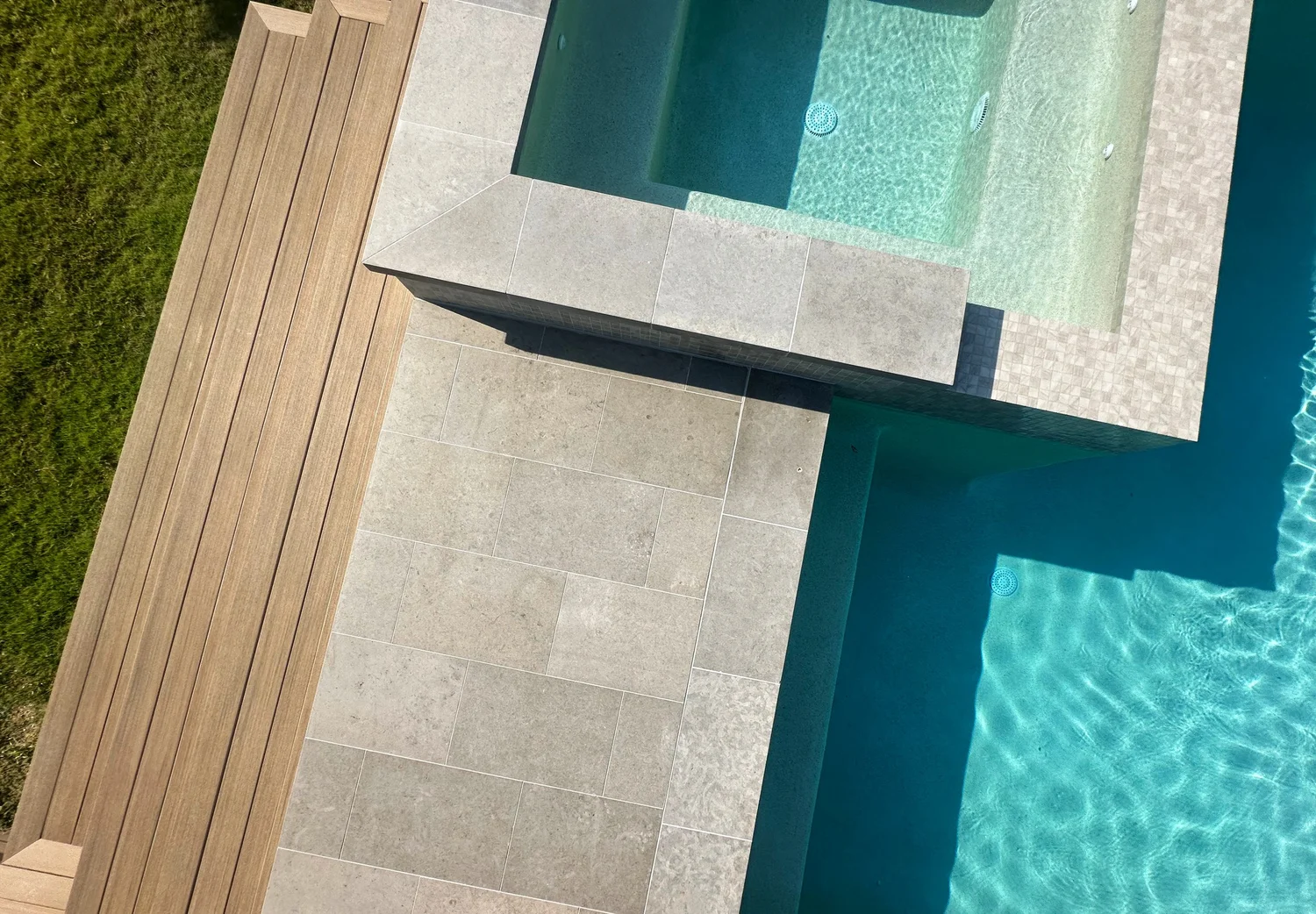 Wood and overlay deck wrapping a pool and spa