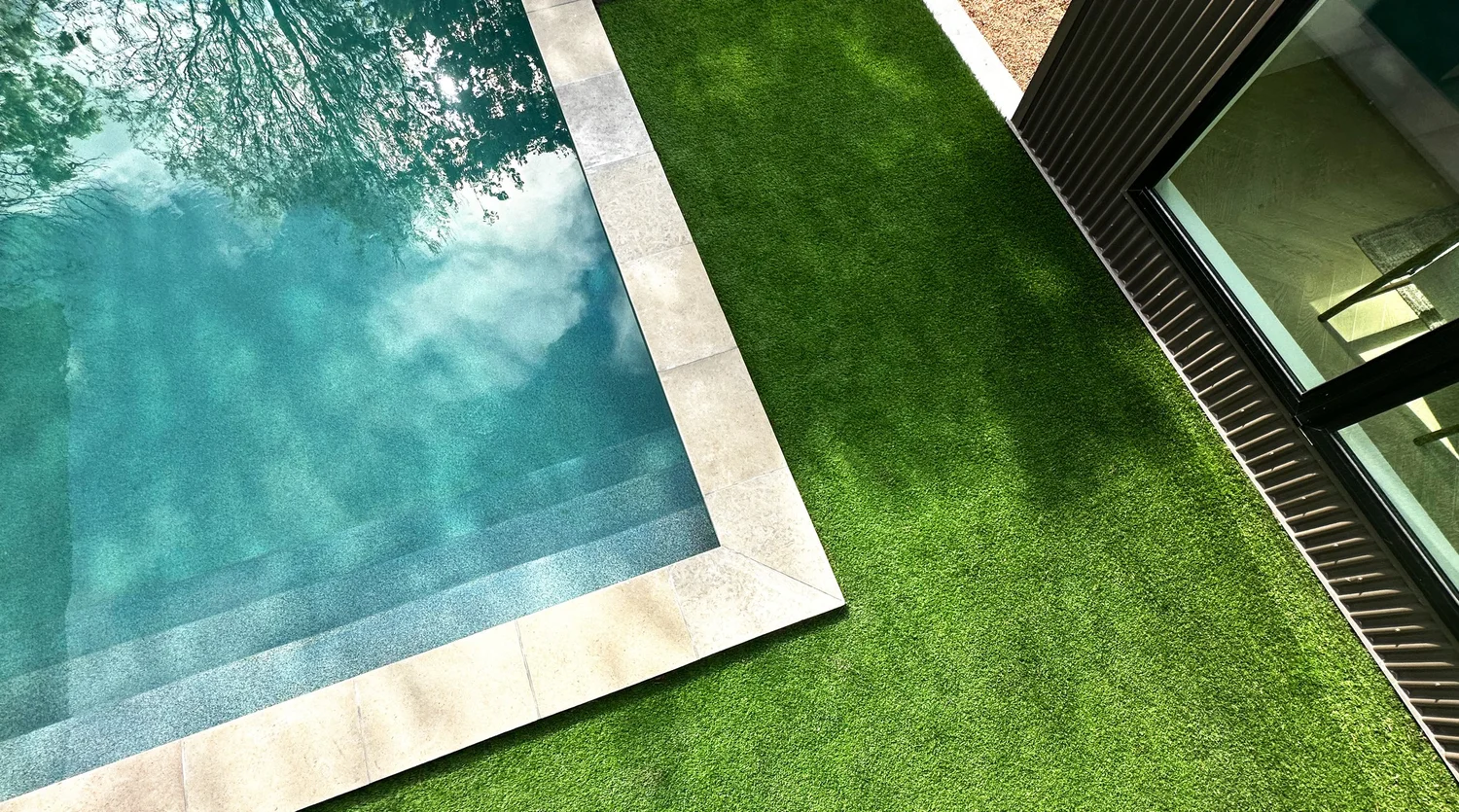 Steps, coping and turf around a finished pool with a backhouse